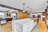 Kitchen featuring open floor plan, light wood-style floors, open shelves, pendant lighting, and beam ceiling