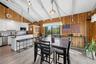Vaulted wood-paneled ceiling with exposed beams, white cabinetry, stainless steel appliances, and wood-finish flooring