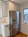 Kitchen with light wood-type flooring, white cabinetry, stainless steel refrigerator with ice dispenser, and tasteful backsplash
