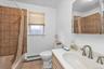 Bathroom with vanity, shower / bath combination with curtain, a baseboard heating unit, and light tile patterned floors