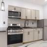Kitchen featuring appliances with stainless steel finishes, backsplash, dark stone counters, decorative light fixtures, and gray cabinets