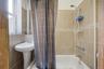 Bathroom featuring shower / bathtub combination with curtain and tile walls