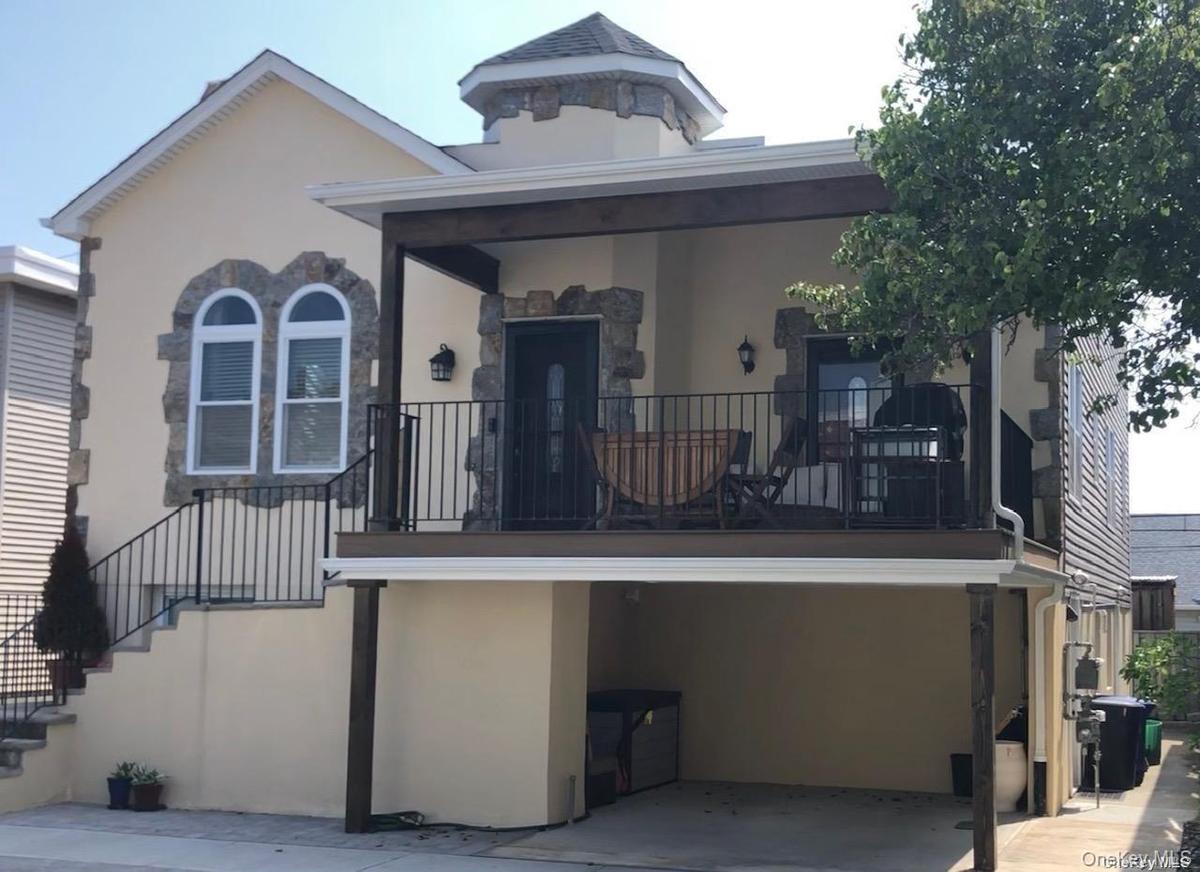 View of front facade with stucco siding, stairway, and a balcony