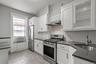 Kitchen with stainless steel appliances, white cabinetry, dark stone countertops, decorative backsplash, and wood tiled floors