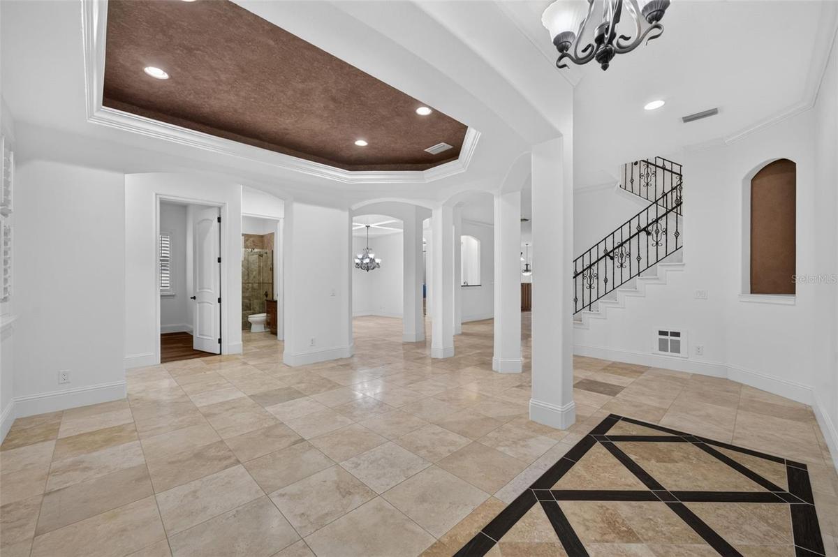 Living Room features a tray ceiling, travertine flooring & high ceilings