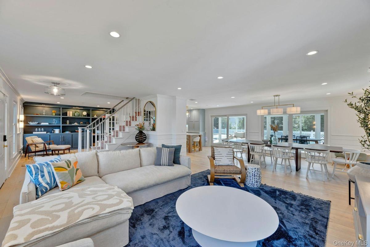 Living area featuring wood finished floors, stairs, a decorative wall, recessed lighting, and built in features