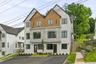 Modern multi-story exterior with white siding, stone accents, and wood-finish paneling