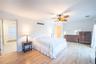 Bedroom featuring a baseboard radiator, light wood-style flooring, visible vents, a ceiling fan, and crown molding