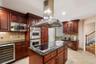 Kitchen featuring a large central island with a built-in cooktop, stainless steel range hood, stainless steel double wall ovens, built-in microwave, a