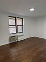 Spare room with an AC wall unit, radiator heating unit, wood finished floors, and a wealth of natural light