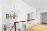 Hall featuring an upstairs landing, plenty of natural light, lofted ceiling, a chandelier, and light carpet