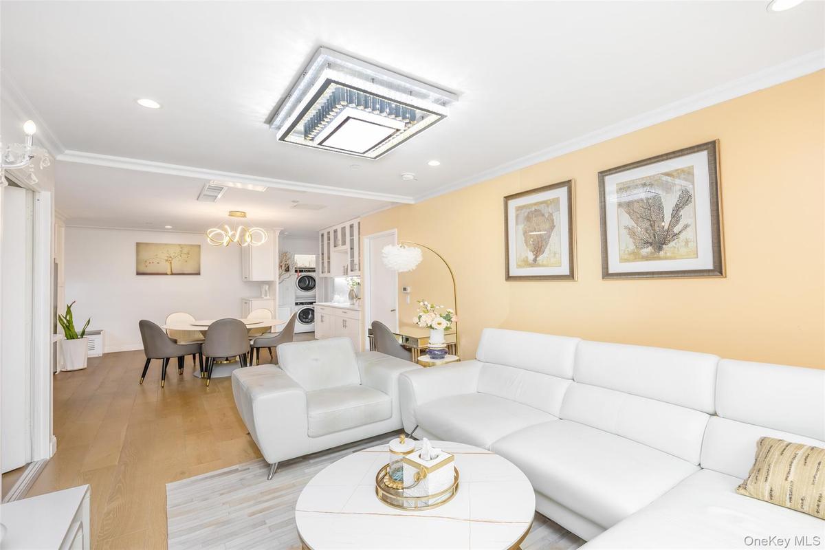 Living room featuring recessed lighting, ornamental molding, wood finished floors, and stacked washer / dryer