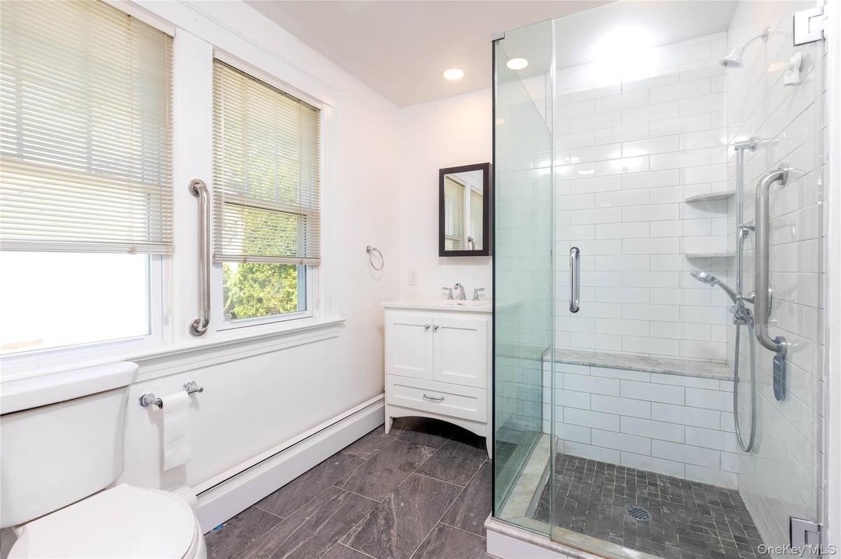 1 st flloor full bathroom. Glass-enclosed shower with white subway tile, a built-in bench, and dual shower heads
