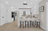 Modern kitchen featuring white cabinetry, light wood-finish flooring, stainless steel appliances, a breakfast bar, and a patterned tile backsplash