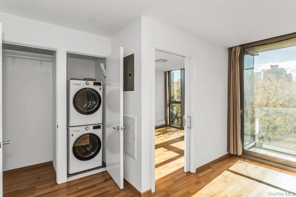 Laundry area featuring estacked washer and dryer, wood finished floors, and electric panel
