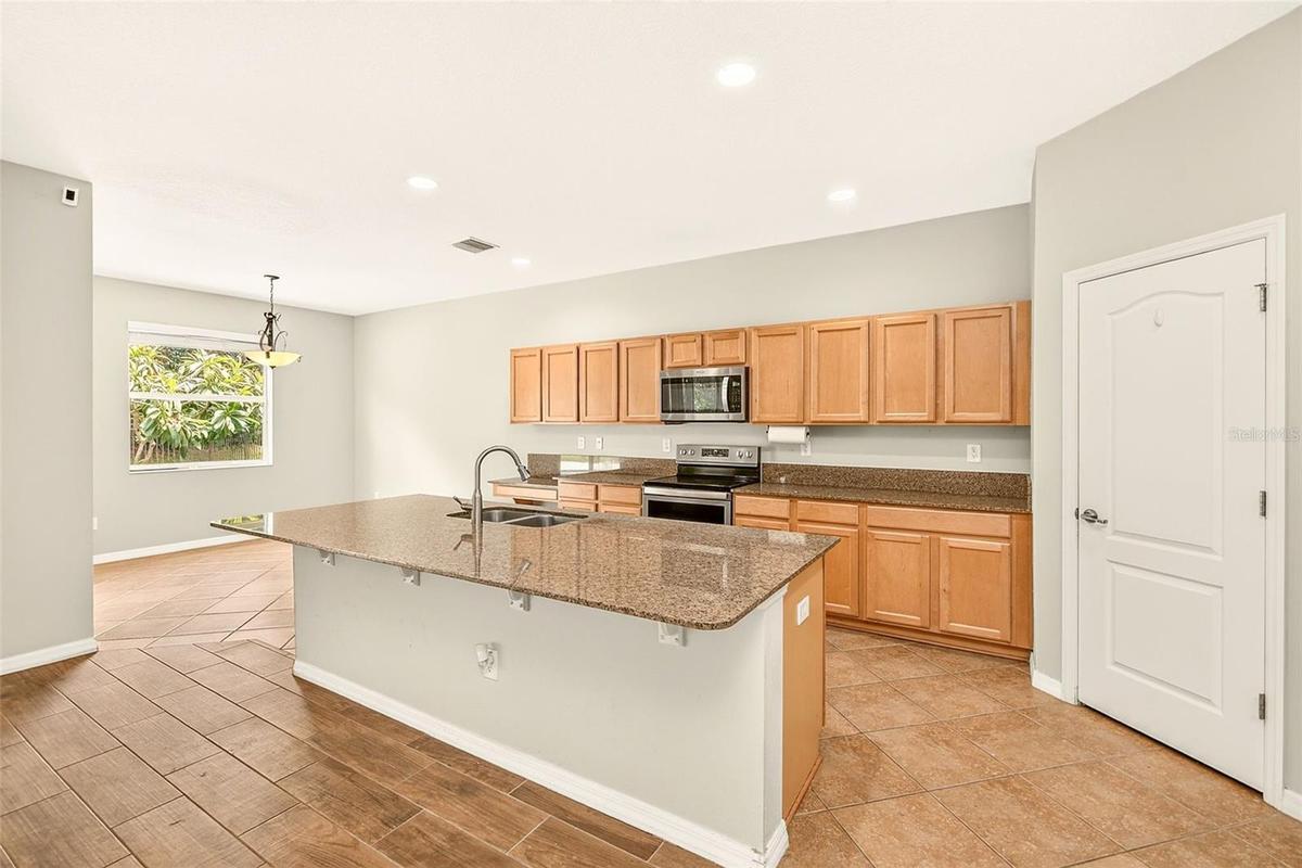 Spacious kitchen featuring stainless steel appliances, large island, granite countertops and an eat in dining area