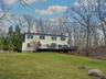 Rear view of house featuring a deck, a yard, a chimney, and view of wooded area