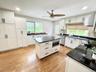 Kitchen with light wood-style floors, crown molding, ceiling fan, white cabinetry, and dark stone counters