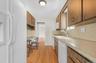 Kitchen featuring wood-finish flooring, wood cabinetry, built-in appliances, and a window above the sink