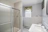 Bathroom featuring a tub/shower combination with sliding frosted glass doors, white subway tile walls, and a decorative tile accent band ( Main Floor)