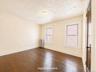 2nd fl  Hardwood flooring, two windows with white trim, wall-mounted radiator, and a wood panel door with dark hardware