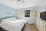 Bedroom featuring wood-finish flooring, a ceiling fan with integrated lighting, and a single window with a dark frame