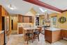 Kitchen featuring brown cabinetry, a skylight, decorative backsplash, island range hood, and stainless steel appliances