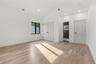 Spacious room featuring vaulted ceilings, light wood-finish flooring, recessed lighting, and a black-framed window