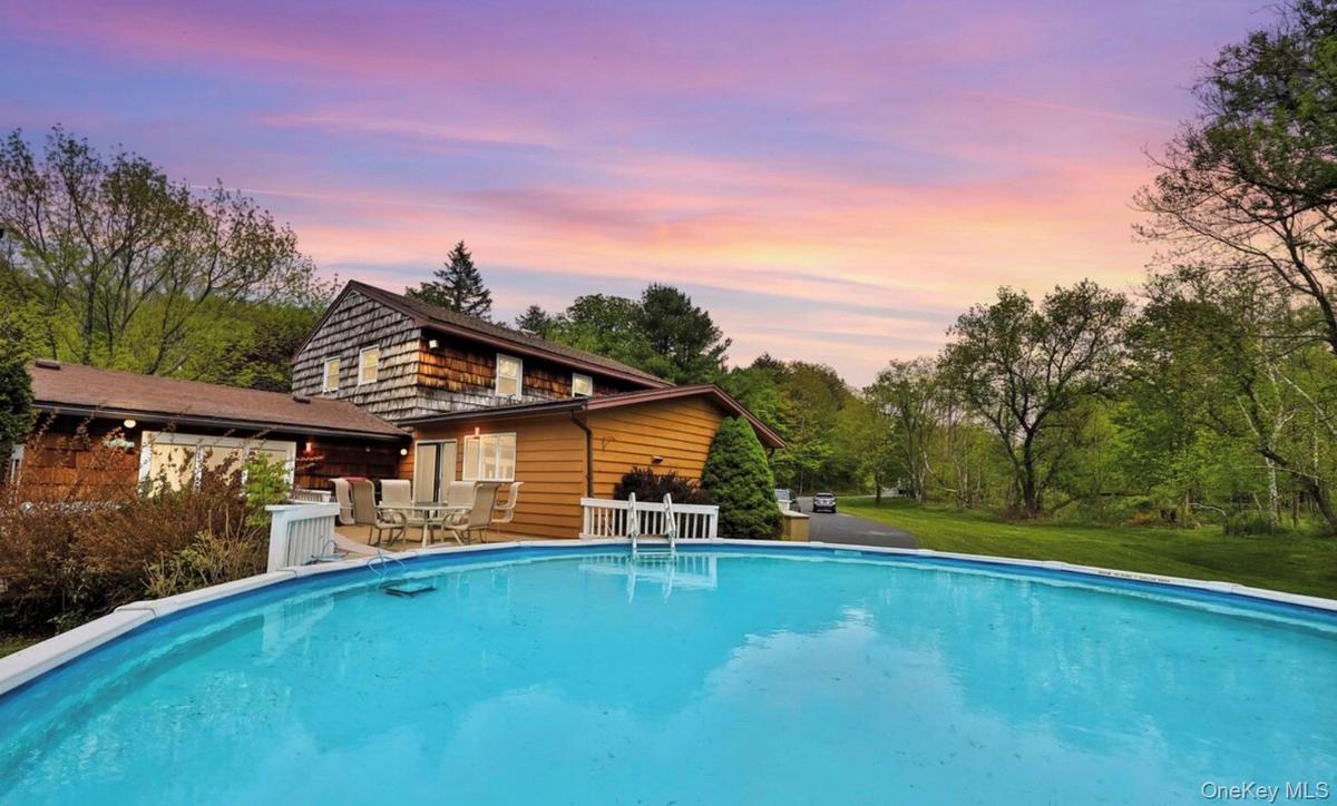 Back of house featuring an outdoor pool, a patio, and a yard