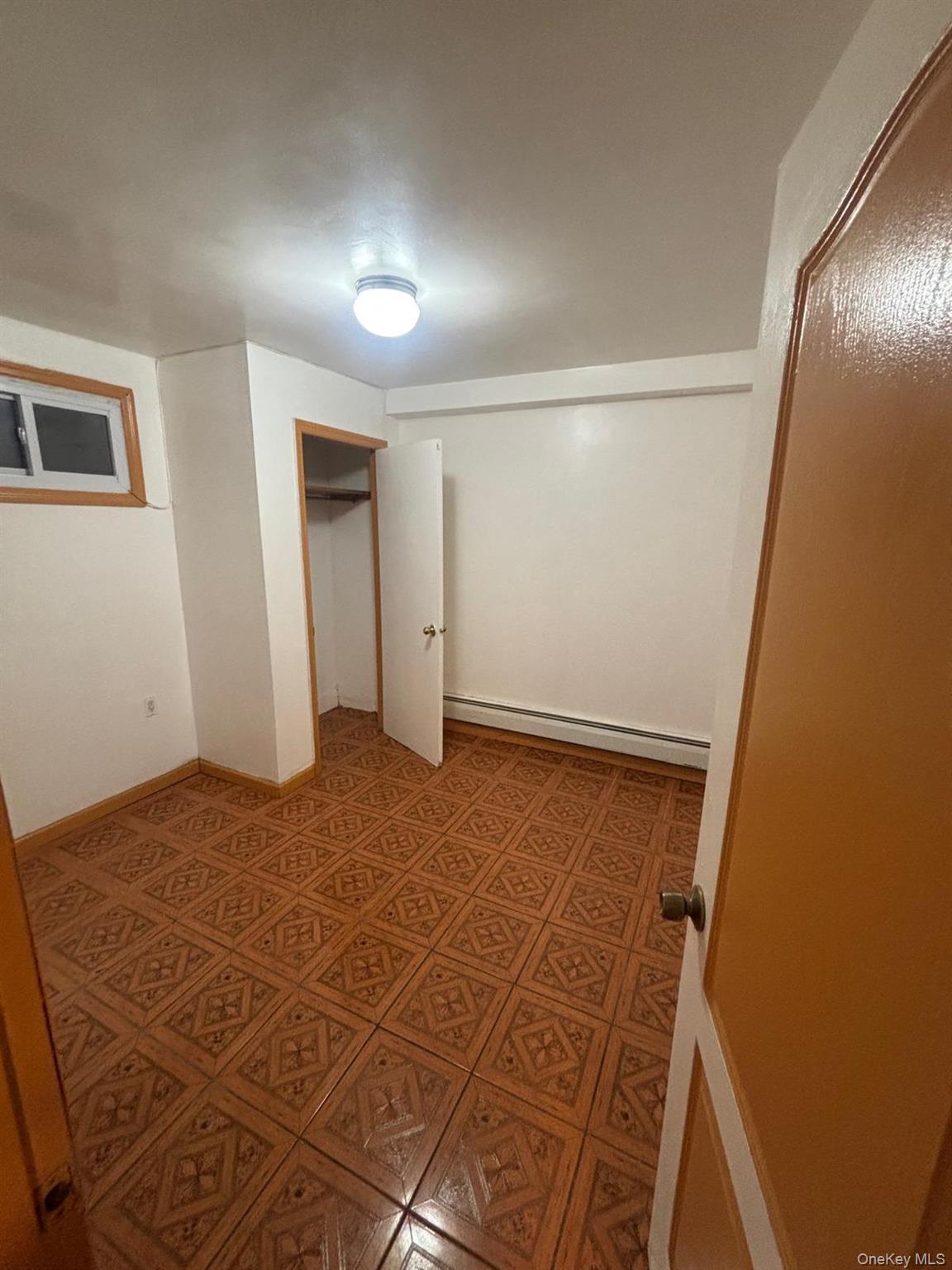 Unfurnished bedroom with a closet, baseboard heating, and light flooring