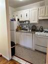 Kitchen featuring tasteful backsplash, white appliances, white cabinetry, and under cabinet range hood