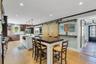 Kitchen featuring white cabinets, glass insert cabinets, a center island with sink, decorative light fixtures, and light wood-style floors
