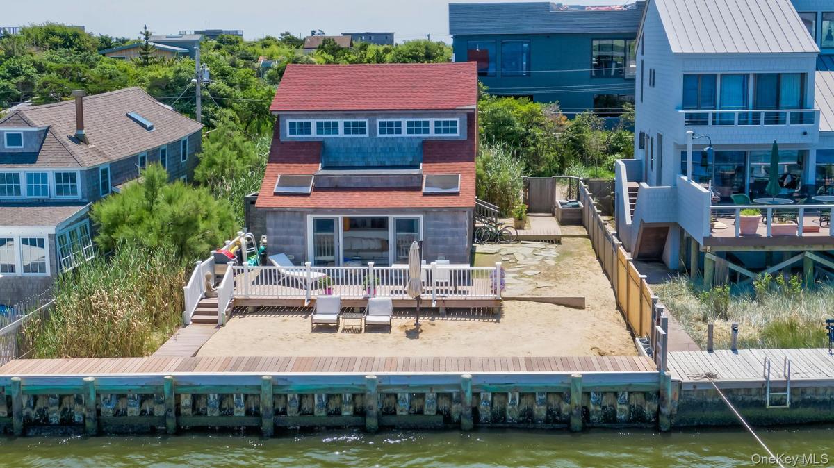 Waterfront property featuring a private wood dock and a sand-covered yard
