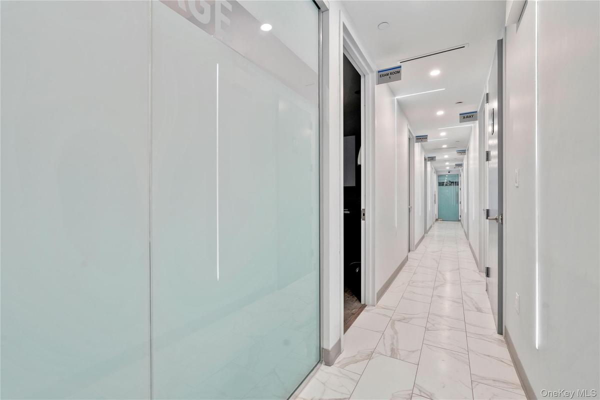 Hall featuring light marble finish flooring and recessed lighting