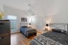 Bedroom with lofted ceiling, light wood-type flooring, a ceiling fan, and a skylight