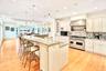 Chefs Kitchen featuring backsplash, Viking range with two ovens, a spacious island, light stone counters, and wall chimney exhaust hood.