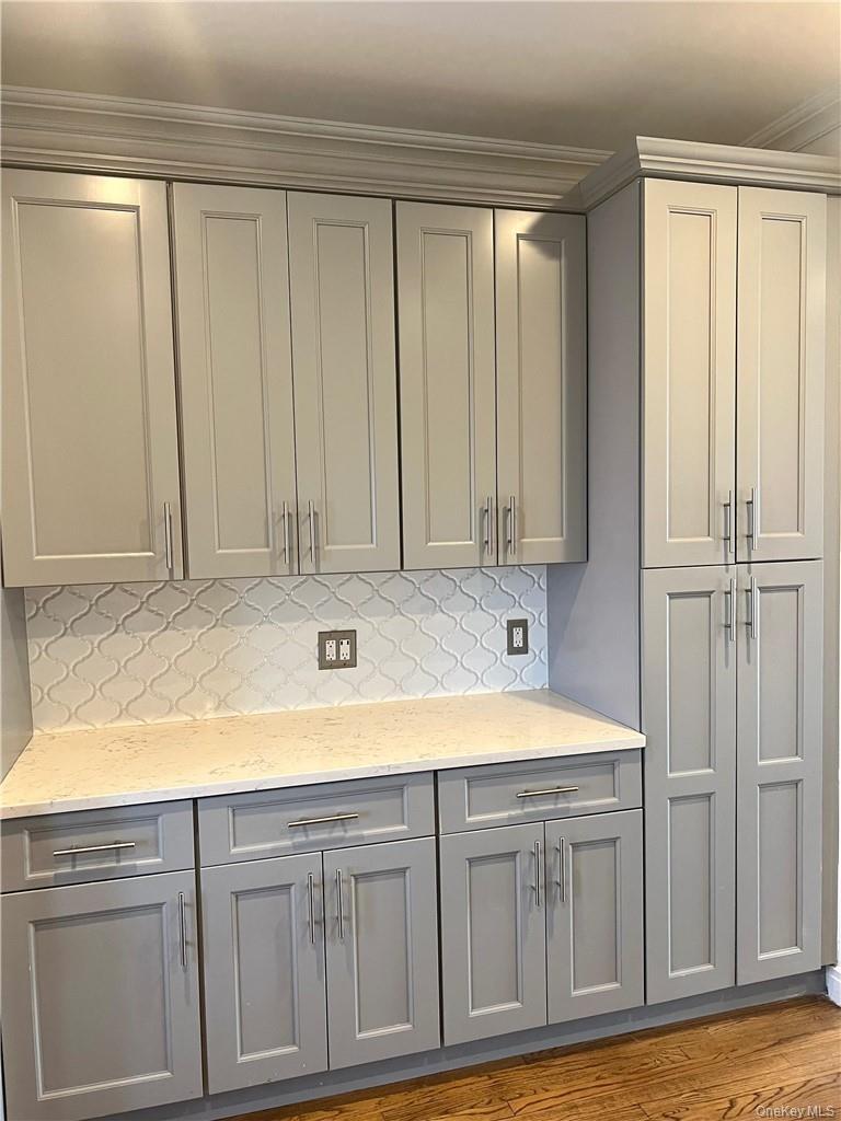 This gorgeous room features lots of sumptuous wooden cabinets (including that pantry), stainless steel appliances and quartz counter tops!
