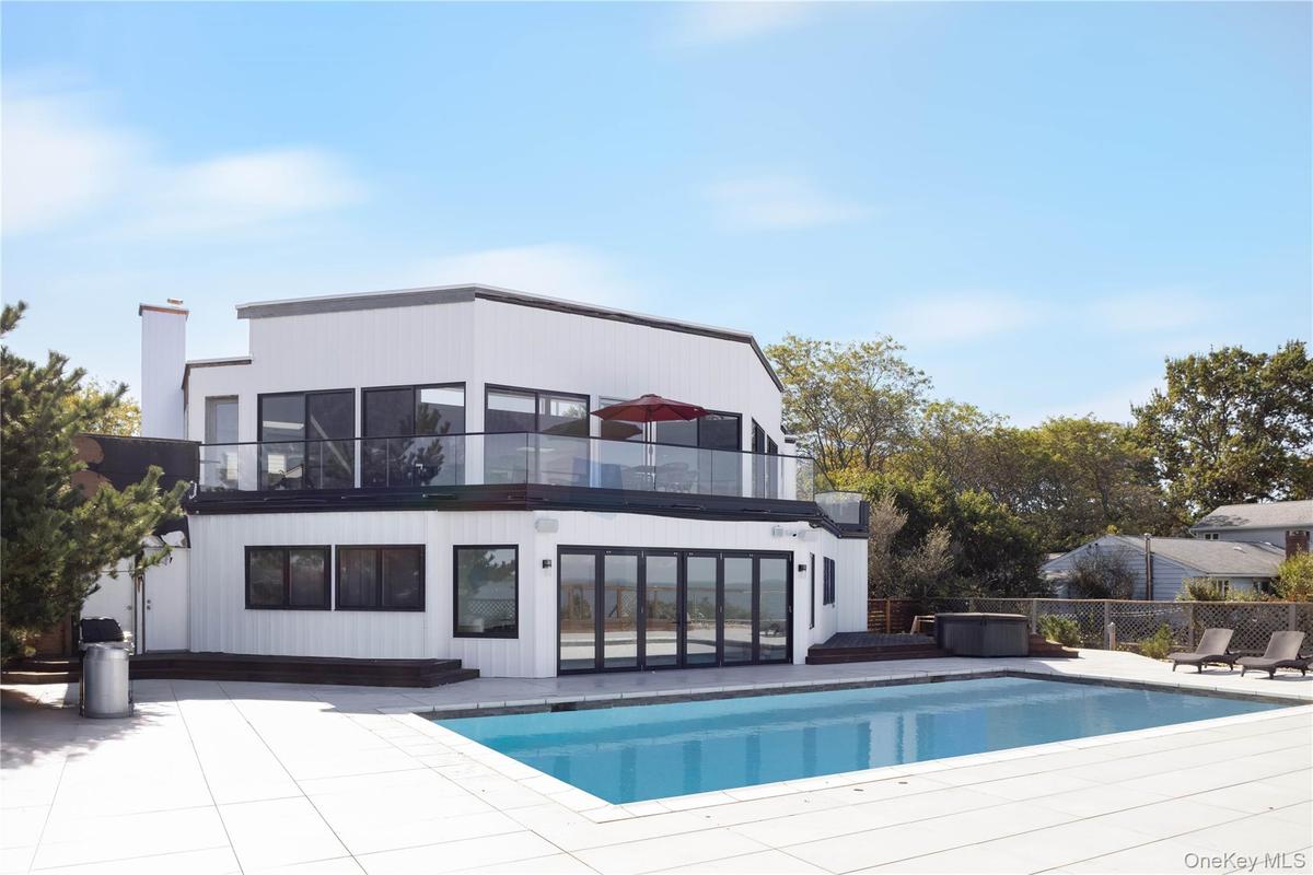 Rear view of property featuring a patio, a fenced in pool, a chimney, and a balcony