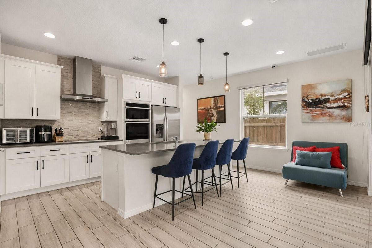 Modern kitchen featuring a large center island with seating, built-in appliances, solid surface countertops, and abundant cabinetry.