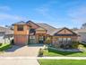 Elegant Sanford, FL home with striking stone façade, barrel tile roof, and an expansive paver driveway that enhances its upscale curb appeal.