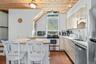 Kitchen featuring wood-paneled ceilings, white cabinetry, stainless steel appliances, and terra cotta floor tiles