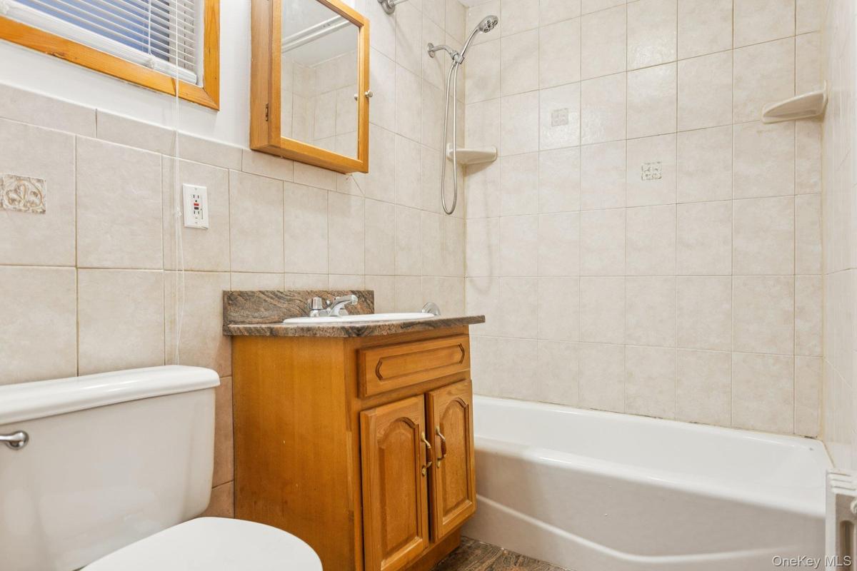 Bathroom featuring tile walls, vanity, shower combination, and decorative backsplash