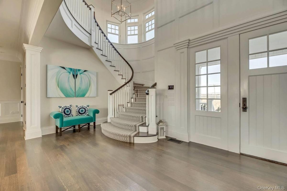 Entryway featuring plenty of natural light, a high ceiling,  wood finished floors, a decorative wall, and stairway