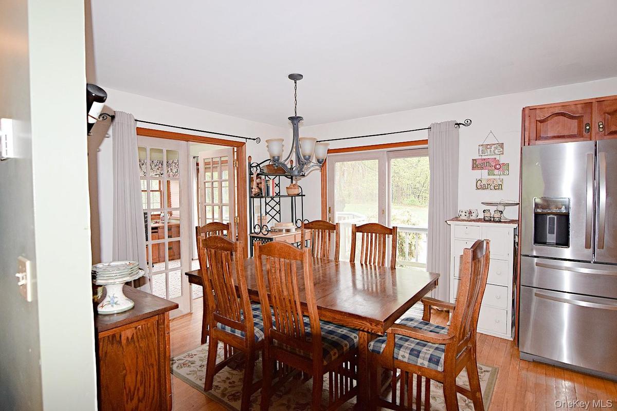 Dining area featuring wood-finish flooring, a contemporary chandelier, and a stainless steel refrigerator