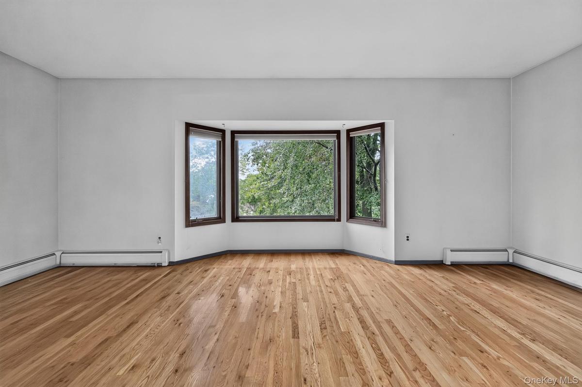 Hardwood flooring throughout, a bay window with trim, and light-toned walls