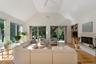 Living area with light wood-type flooring, a high end fireplace, high vaulted ceiling, and built in shelves