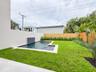 (as of April 8, 2026) view of spa pool and backyard from patio, clusia grows quickly and will be taller than fence by end of year