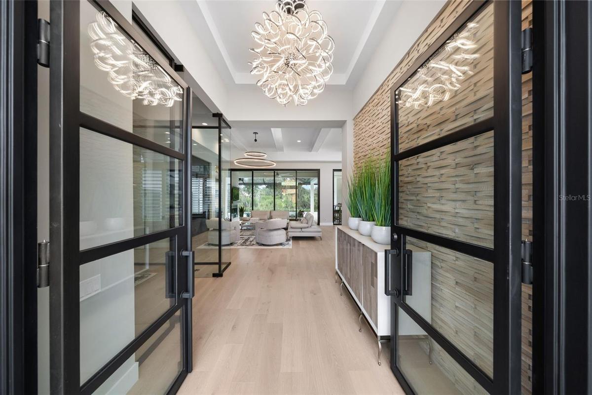 The architectural presence of the home is immediately evident as you enter the foyer through breathtaking 10-foot glass and iron entry doors.