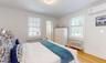Bedroom with wood-type flooring, radiator heating unit, ensuite bathroom, and crown molding