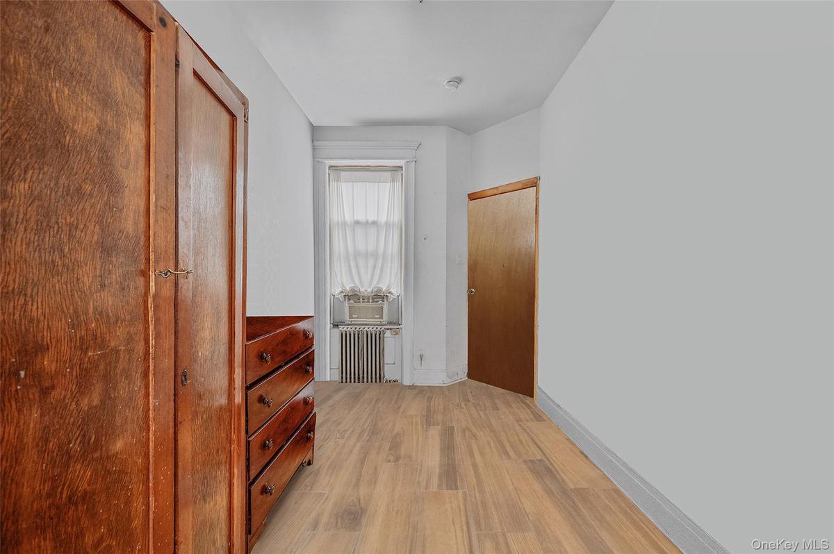 Corridor featuring light wood finished floors and radiator heating unit